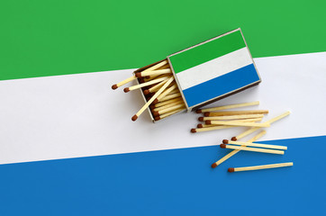 Sierra Leone flag  is shown on an open matchbox, from which several matches fall and lies on a...