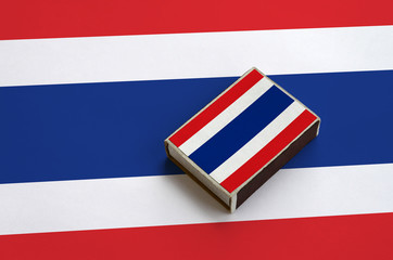 Thailand flag  is pictured on a matchbox that lies on a large flag