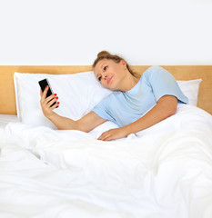 Woman relaxing on her bed,using smarthone