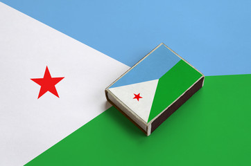 Djibouti flag  is pictured on a matchbox that lies on a large flag