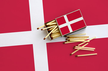 Denmark flag  is shown on an open matchbox, from which several matches fall and lies on a large flag