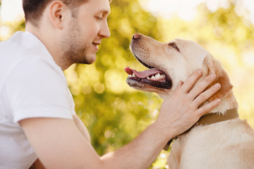 Owner young man with labrador dog outdoors green grass. Concept friendship