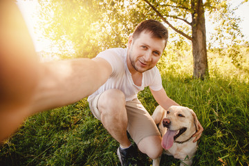Man is smile fun with their dog labrador retriever outdoors. Making selfie. Concept friendship