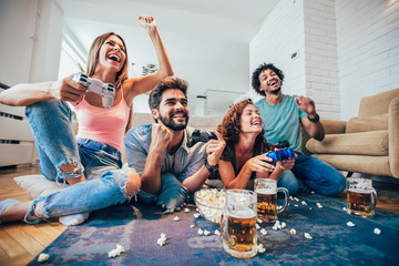 Group of friends play video games together at home, having fun.