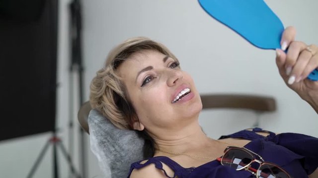 Patient in dental clinic on chair smiling with veneers