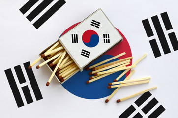 South Korea flag  is shown on an open matchbox, from which several matches fall and lies on a large...
