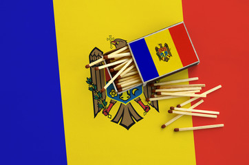 Moldova flag  is shown on an open matchbox, from which several matches fall and lies on a large flag