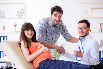 Fototapeta premium Pregnant woman with her husband visiting the doctor in clinic