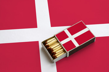 Denmark flag  is shown in an open matchbox, which is filled with matches and lies on a large flag