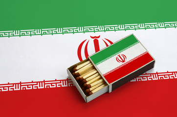 Iran flag  is shown in an open matchbox, which is filled with matches and lies on a large flag