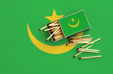 Mauritania flag  is shown on an open matchbox, from which several matches fall and lies on a large...