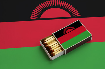 Malawi flag  is shown in an open matchbox, which is filled with matches and lies on a large flag