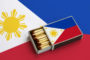 Philippines flag  is shown in an open matchbox, which is filled with matches and lies on a large...