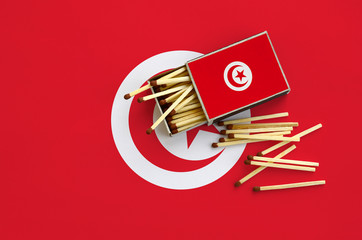 Tunisia flag  is shown on an open matchbox, from which several matches fall and lies on a large flag