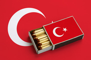 Turkey flag  is shown in an open matchbox, which is filled with matches and lies on a large flag