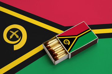 Vanuatu flag  is shown in an open matchbox, which is filled with matches and lies on a large flag