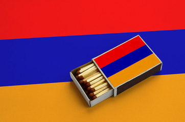 Armenia flag  is shown in an open matchbox, which is filled with matches and lies on a large flag
