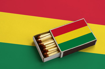 Bolivia flag  is shown in an open matchbox, which is filled with matches and lies on a large flag
