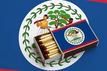 Belize flag  is shown in an open matchbox, which is filled with matches and lies on a large flag