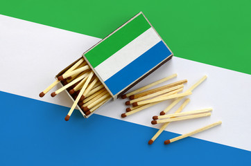 Sierra Leone flag  is shown on an open matchbox, from which several matches fall and lies on a...