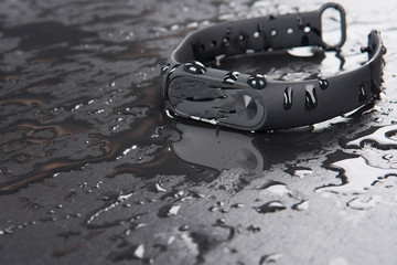 Fitness bracelet on a black slate background with drops of water