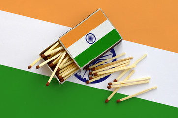 India flag  is shown on an open matchbox, from which several matches fall and lies on a large flag