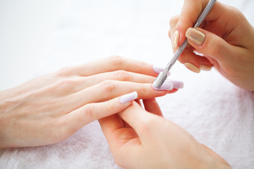 Obraz na płótnie Canvas SPA manicure. French manicure at spa salon. Woman hands in a nail salon receiving a manicure procedure. Manicure procedure