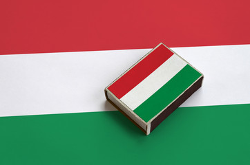 Hungary flag  is pictured on a matchbox that lies on a large flag