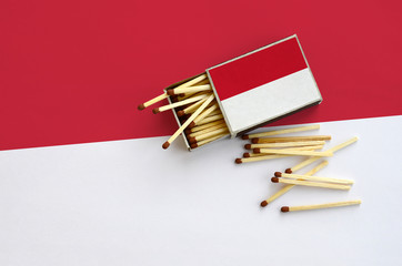 Indonesia flag  is shown on an open matchbox, from which several matches fall and lies on a large...