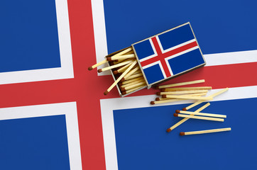 Iceland flag  is shown on an open matchbox, from which several matches fall and lies on a large flag