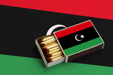 Libya flag  is shown in an open matchbox, which is filled with matches and lies on a large flag