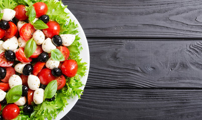 Salad with basil , tomatoes , olives and mozzarella