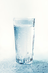 Glass of cold water with drops and reflection, toned. Drink of health freshness aqua