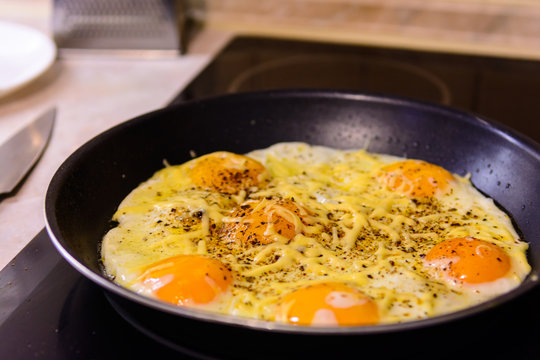 Fried eggs in the frying pan with cheese at home.