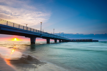 Fototapeta na wymiar quiet beach with pier at sunset, long time exposure
