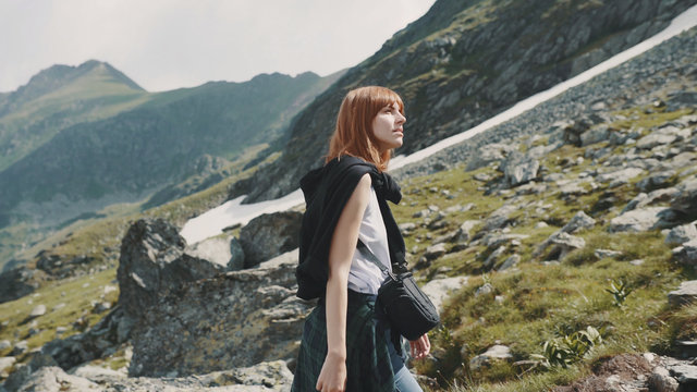 A young woman hiker walks in the mountains with photo camera. Transfagarasan, Carpathian mountains in Romania