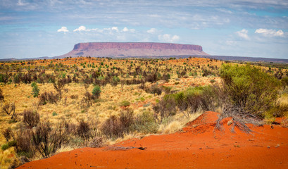 Mount Conner in the outback on a sunny day with white clouds in the background