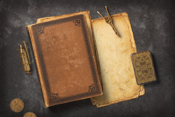 Steampunk / Gaslight themed mockup with a vintage book, a stack of grungy paper and antique brass...