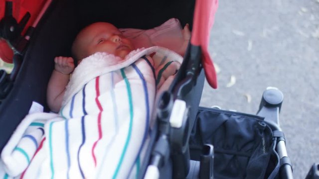 Camera follows a young baby in a pram, in slow motion 