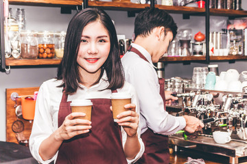 Portrait of woman small business owner smiling and holding coffee behind the counter bar in a...
