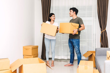 Happy young couple holding box and moving into their new home.House moving and real estate concept