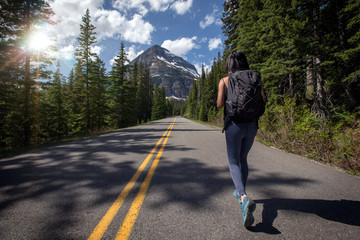 Solo female adventurer and nomadic wanderlust world traveller walking on long journey, backpacking on empty road 