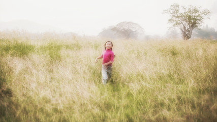 little girl running on the lawn in the city park outdoor; Freedom and carefree. Happy childhood; happy children running around outside.