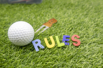 Naklejka premium Rules of golf with golf ball and wording rules are on green grass