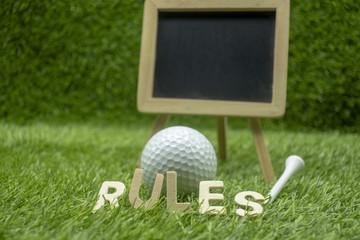 Rules of golf with golf ball and wording rules are on green grass