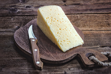 cheese and knife on a wooden board