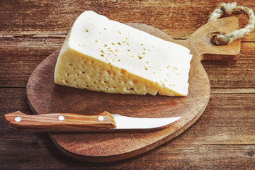 cheese and knife on a wooden board