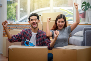 Asian young couple are glad after successfull packing the big cardboard box for moving in new place, Moving and House Hunting concept,