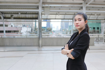 Confident young Asian business woman crossing one's arms at outside office.