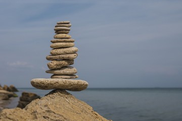 Fototapeta na wymiar balancing pyramid of stones on a large stone on the seashore